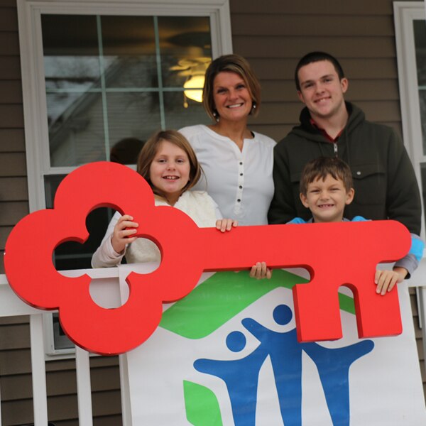 A Columbus Mid-Ohio Habitat for Humanity family holding a large red KeyBank key
