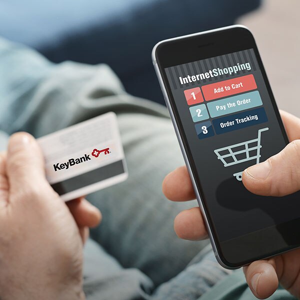 Person using their smartphone and KeyBank commercial card to shop online