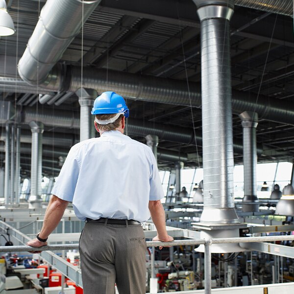 Man wearing hardhat looking out over factory