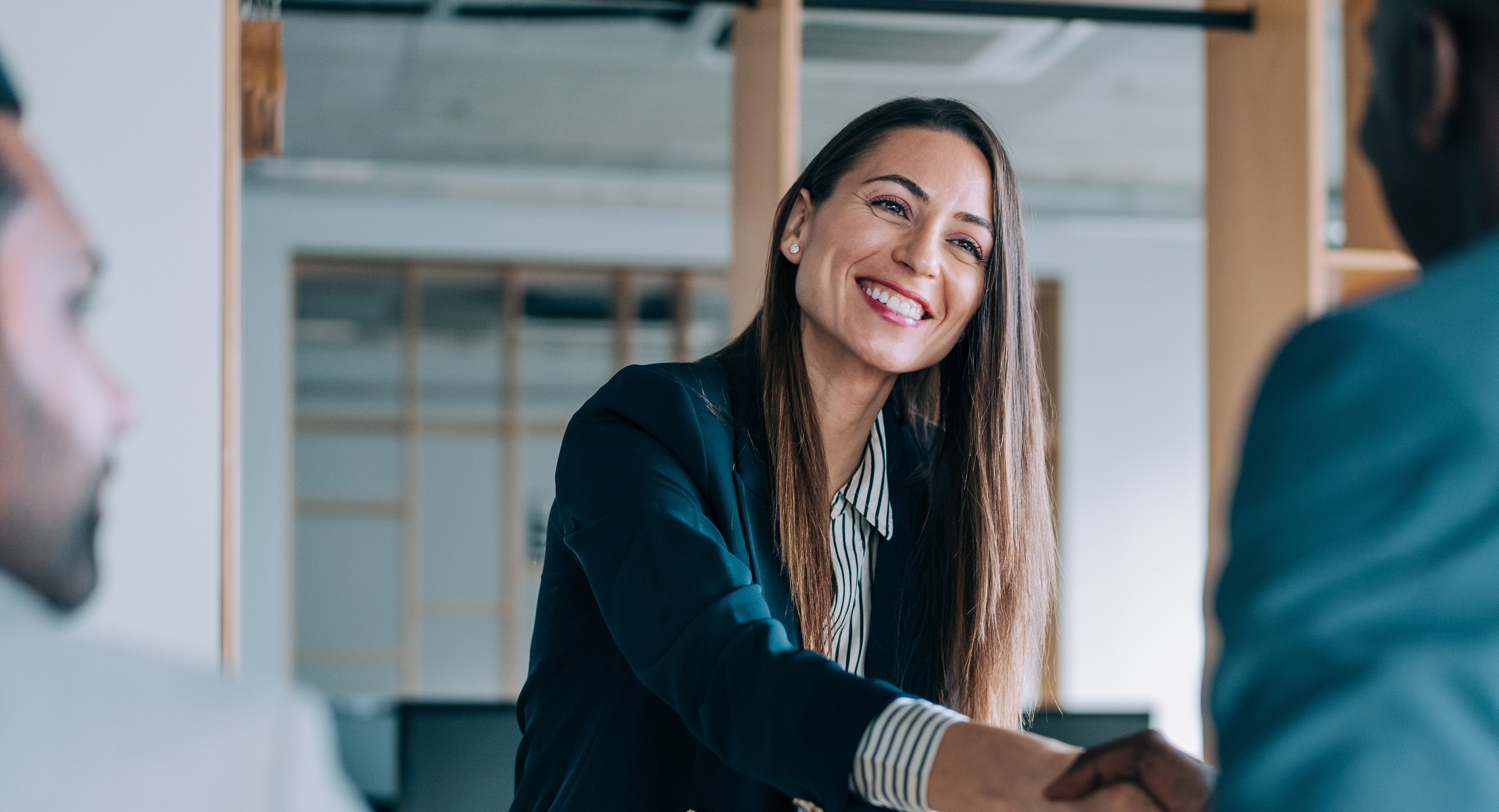 Business people shaking hands in the office. Group of business persons in business meeting. Three entrepreneurs on meeting in board room. Corporate business team on meeting in modern office. Female manager discussing new project with her colleagues. Company owner on a meeting with two of her employees in her office.