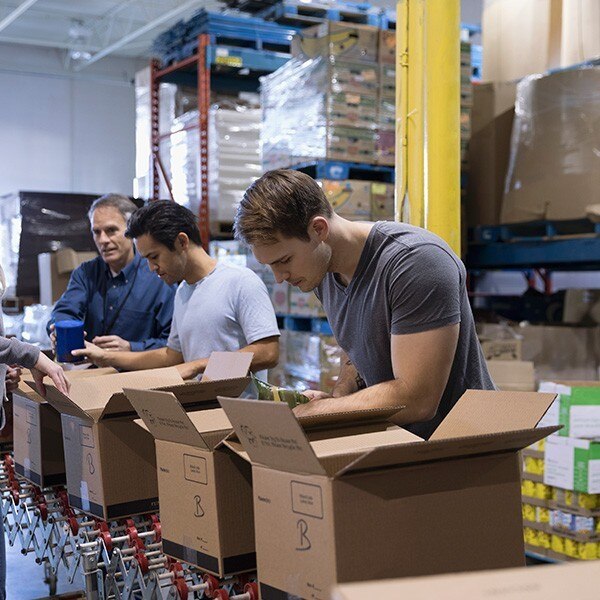 Volunteers boxing food in warehouse