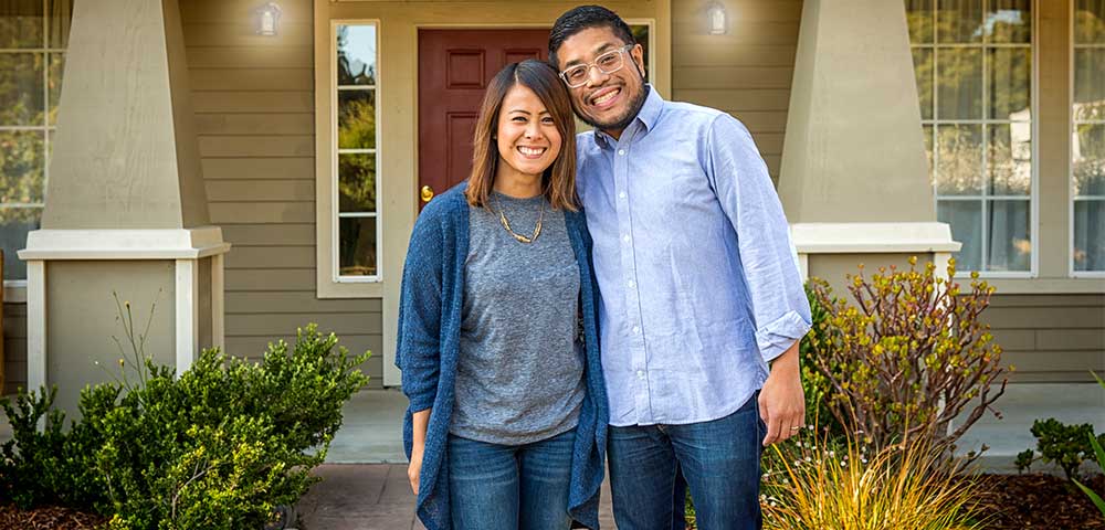 Man and woman standing in front of new home