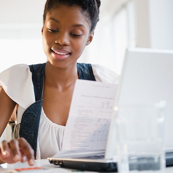 Woman sitting in front of laptop with papers in hand