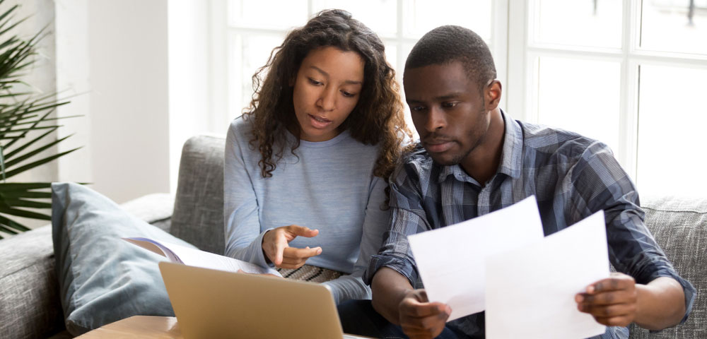 Couple sitting on couch holding papers
