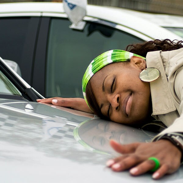 Young woman hugging the hood of a car