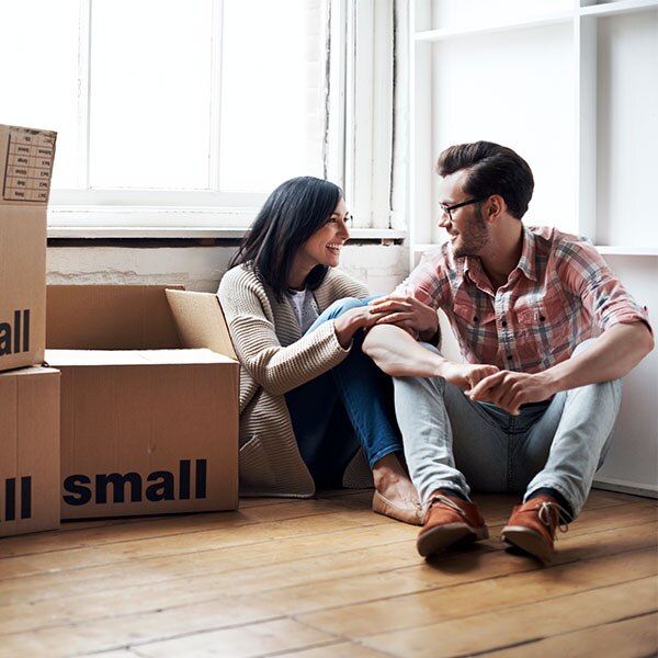Man and woman sitting next to a pile of moving boxes