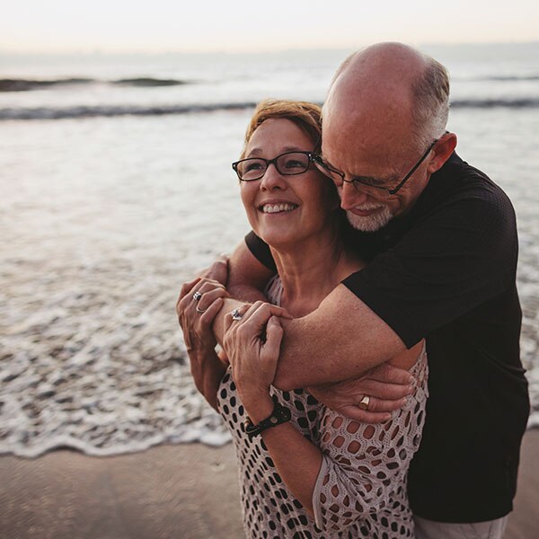 Older couple hugging in front of the ocean