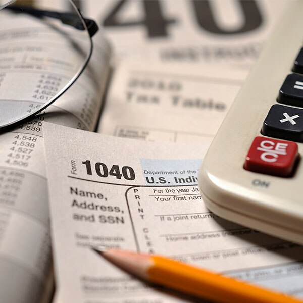 Pencil, calculator and glasses sitting on top of tax forms