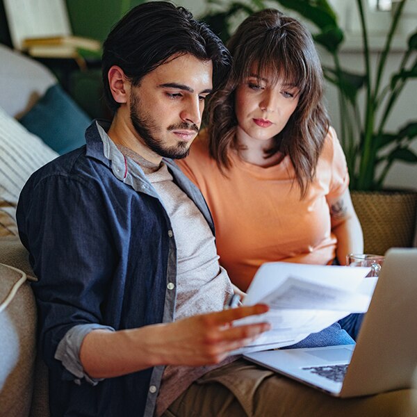 two people looking at papers and laptop
