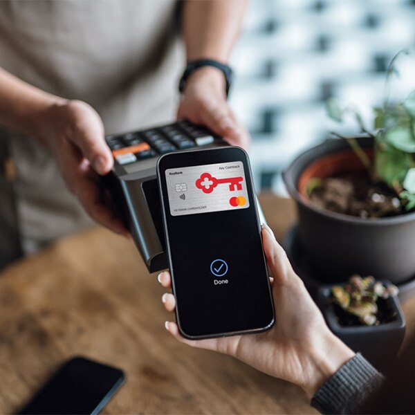 hand holding phone over hand held payment processor