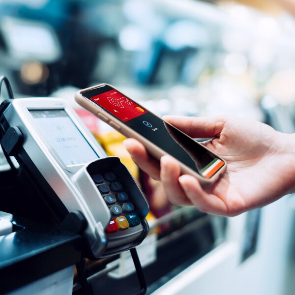 hand holding cell hone over payment processor