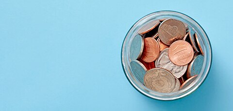 Overhead view of jar of coins on blue background