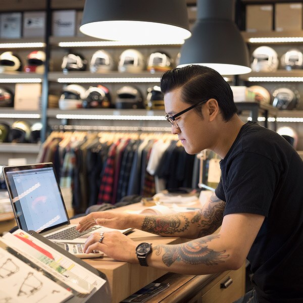 Man working in a store with a laptop and calculator
