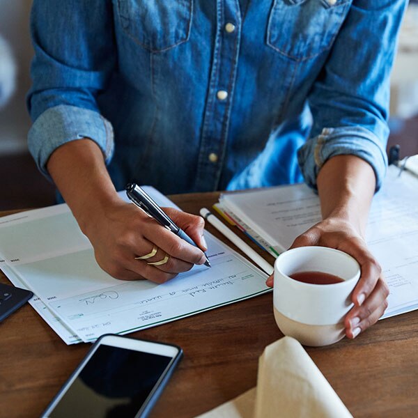 person drinking coffee writing a check