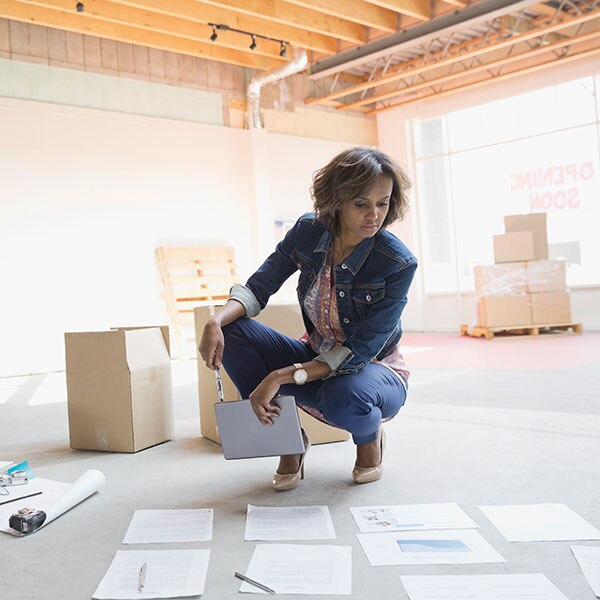 woman crouching on floor looking at documents
