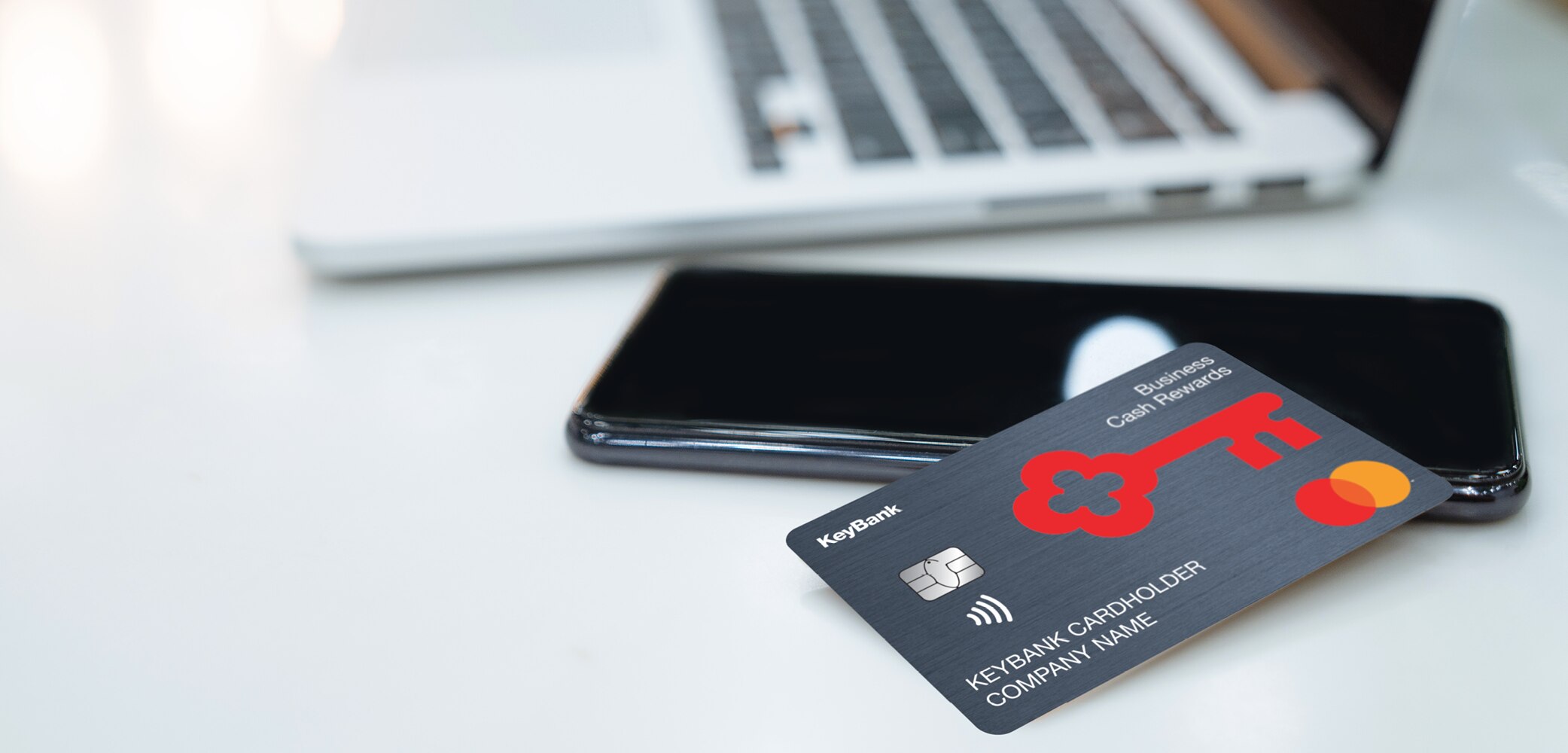 Laptop, mobile phone and Business Cash Rewards card on table