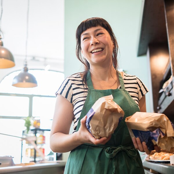 woman in bakery holding loaves of bread