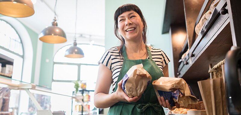woman in bakery holding loaves of bread