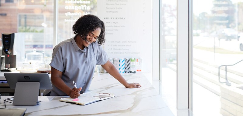 woman in shop writing in a ledger