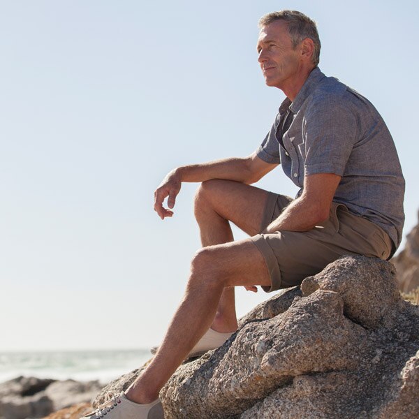 Man sitting on rock staring out at sky