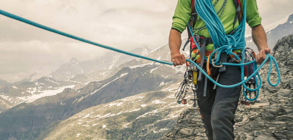 guy climbing mountain with bungees attached to him