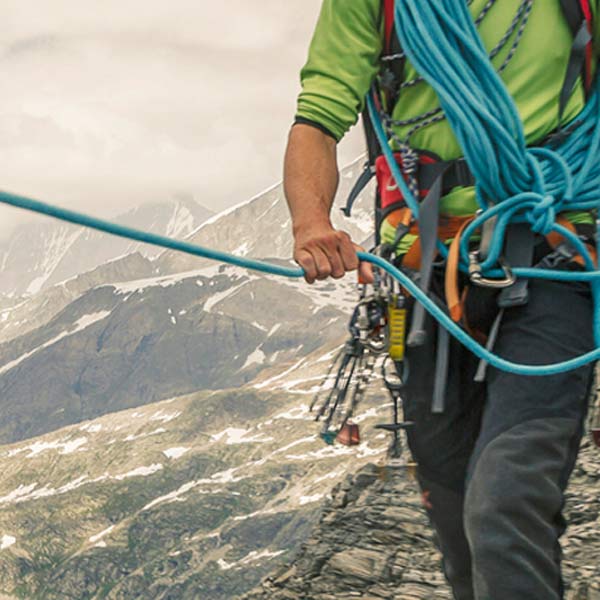 guy climbing mountain with bungees attached to him