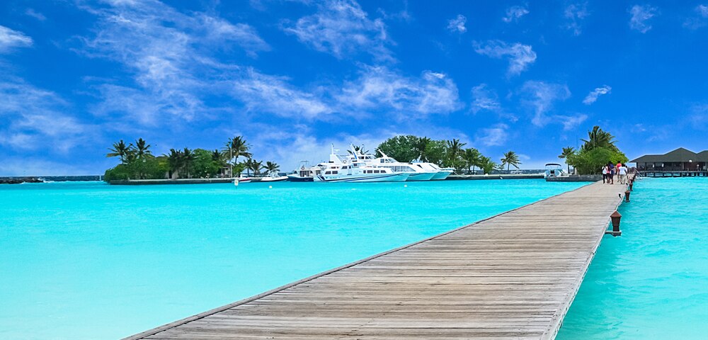 bridge over clear blue water looking back at land and boats