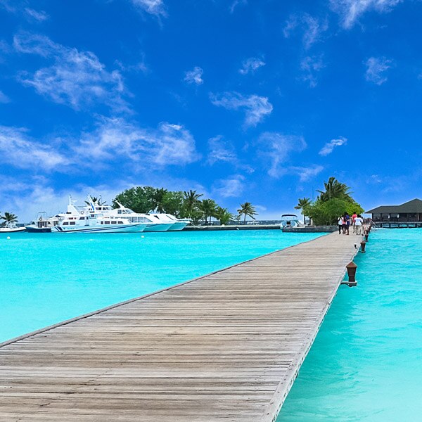 bridge over clear blue water looking back at land and boats