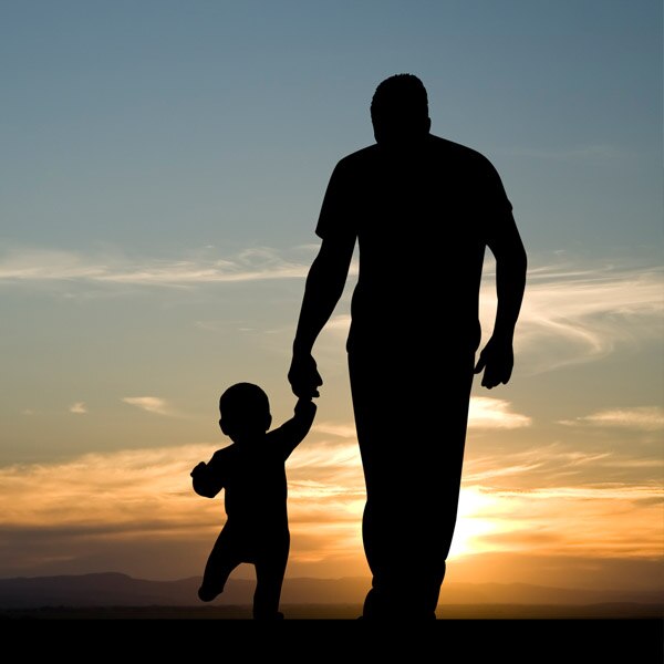 shadow outline of child holding grandfather's hand looking at the sunset sky