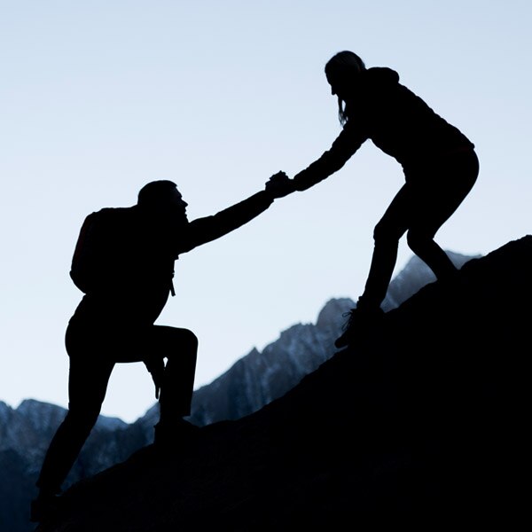woman helping man climb a mountain