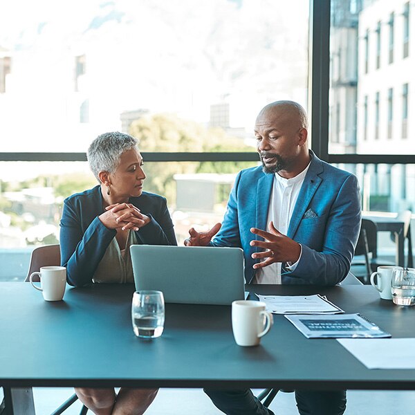 Business, presentation and man on a laptop in a corporate conference or office collaboration with a woman at work. Businessman, manager or coach for marketing, strategy and sales working with CEO.