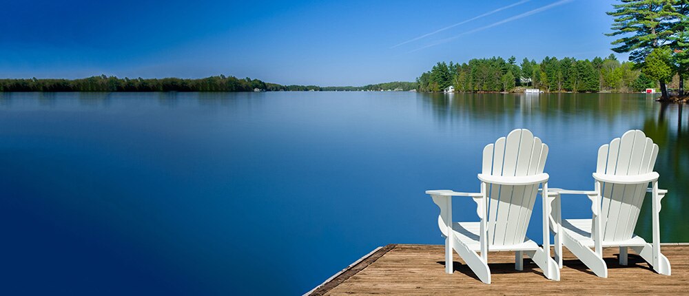 Adirondack chairs on dock by lake