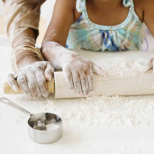 Mother and daughter rolling dough